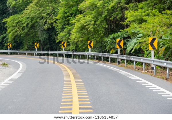 Curve road Car on asphalt road in beautiful spring\
day at countryside Traffic Lines yellow Tree side Slip protection\
danger