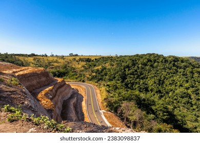 Curve of the road in Serra de Avencas, with the sandstone wall on one side and the vegetation on the other side in the interior of the state of São Paulo, Brazil. - Shutterstock ID 2383098837