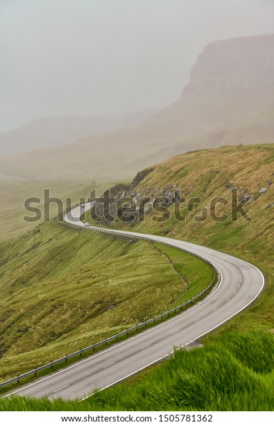 Curved asphalt road in\
foggy mountains