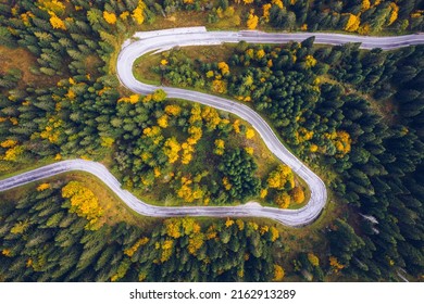 Curved Bending Road In The Forest. Aerial Image Of A Road. Forrest Pattern. Scenic Curvy Road Seen From A Drone In Autumn. Aerial Top Down View Of Zig Zag Winding Mountain Road, Drone Shot.