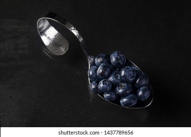 curved chrome spoon with blueberries with drops of water on dark background - Powered by Shutterstock