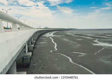 Curved Coastal Concrete Highway Road With Lower Water In The Mud Beach With Blue Sky And Clouds. Road Trip Travel. Summer Journey At Tropical Cement Bunting Bridge. Natural Carbon Sinks.