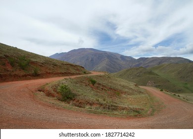 The curved dirt road in the mountains. View of the rural route curve along the hills and green valley. 