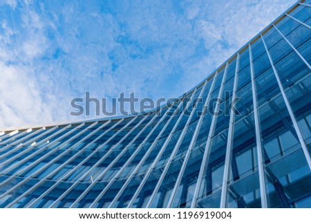 Curved facade of modern glass blue building with sky background