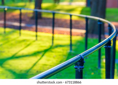 A Curved Fence Railing Of A Suburban Sports Oval In The Late Afternoon Sun And Shallow Depth Of Field