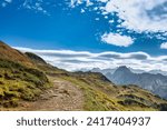 Curved hiking path near Nebelhorn mountain Oberstdorf, Allgäu, with view over distant endless mountain landscape. Shallow depth of field focus on hiking trail