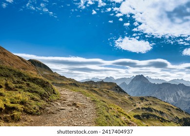 Curved hiking path near Nebelhorn mountain Oberstdorf, Allgäu, with view over distant endless mountain landscape. Shallow depth of field focus on hiking trail - Powered by Shutterstock