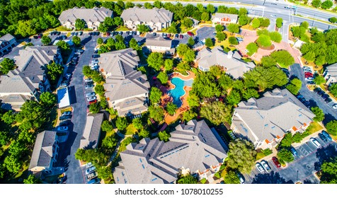 Curved Modern Swimming Pool And Bright Lush Green Trees Surrounding Cozy New Development Suburb Apartment Complex Townhomes - Aerial Drone View - Round Rock , Texas , USA