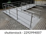 the curved ramp at the entrance to the building is suitable for wheelchair access and supply to the building. stainless steel railing, concrete surface