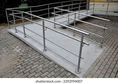 the curved ramp at the entrance to the building is suitable for wheelchair access and supply to the building. stainless steel railing, concrete surface