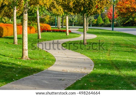 Curved sidewalk, path, trail at the empty street. Neighborhood scenery.