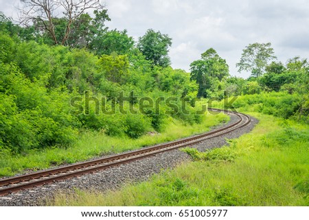 Curved single train track in forest of Thailand. With two parallel iron rails for movement of rail cars.
