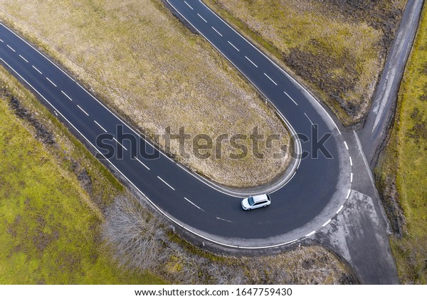 a curved\
street with a car driving from\
above