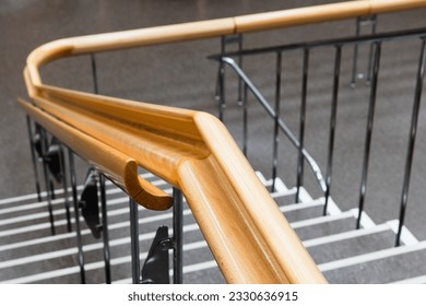 Curved wooden handrail close-up photo with selective soft focus, modern architecture