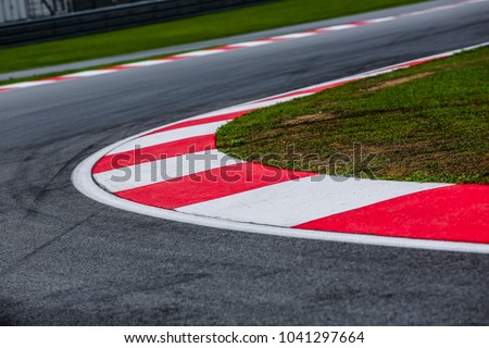 Curving asphalt red and white kerb of a race track detail. Motorsports racing circuit close up.