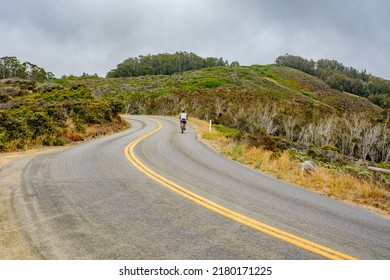 Curving Asphalt Road With Yellow Lines, And Silhouette Of Bicyclist, Serpentine Way