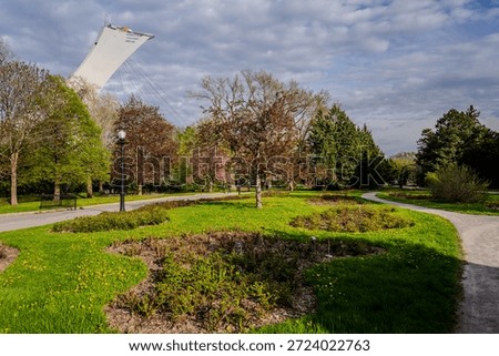 Curving paths and spring foliage fill Jardin botanique as the Montreal Olympic Tower rises above the trees under a cloudy sky. Montreal, Canada - May 12, 2024