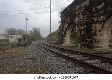 Curving Railroad Track Along Abandoned Rail Overpass On An Overcast Day In The Deep South