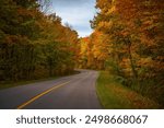 Curvy asphalt parkway road crossing the forest in Gatineau Park during fall rhapsody, colourful autumn foliage, Canadian landscape. Photo taken in Gatineau, Quebec, Canada in October 2022.