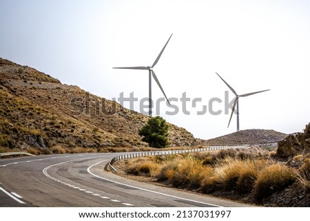 curvy asphalt road to the wind turbines. Green energy. Transport