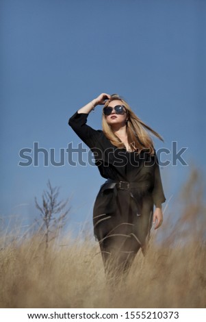 Similar – Kühle blonde Frau mit Sonnenbrille und schwarzem Kleid, die sich bei Sonnenuntergang in der Natur amüsiert.