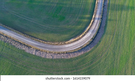Curvy road between 2 fields photographed from above