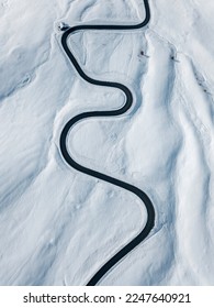 Curvy windy road in snow covered mountain hill. Top down aerial view.  Scenic winter background captured from above. Travel concept. Passo Di Giau,Dolomities,Italy.