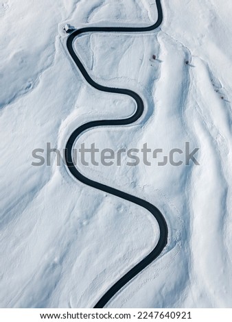 Curvy windy road in snow covered mountain hill. Top down aerial view.  Scenic winter background captured from above. Travel concept. Passo Di Giau,Dolomities,Italy.