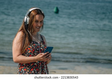 Curvy Woman On The Beach With Phone And Headphones