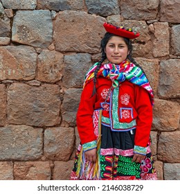 CUSCO, PERU - SEPTEMBER 11, 2018: Portrait of a young Peruvian indigenous Quechua woman with traditional textile clothing in front of Inca wall in Cusco, Sacred Valley of the Inca.