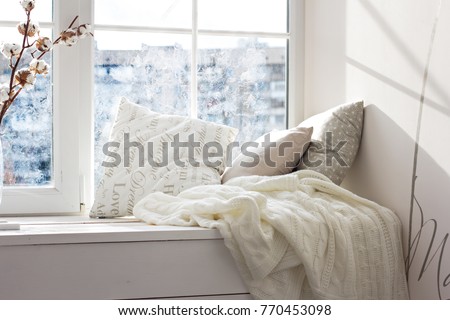cushions and a knitted plaid on the windowsill. A cozy winter window sill. 