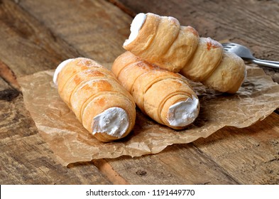 Custard tube of pastry filled with cream - dessert cake - traditional czech sweet on baking paper on wooden table