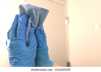 Custodian cleaning a bathroom mirror in a hotel. Housekeeper wearing gloves and using a microfiber cloth