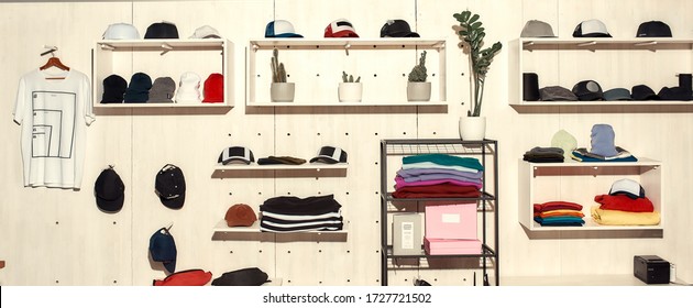 Custom Apparel, Clothes Neatly Arranged Or Folded On Shelves. Stack Of Colorful Clothing And Baseball Caps In The Store. Horizontal Shot