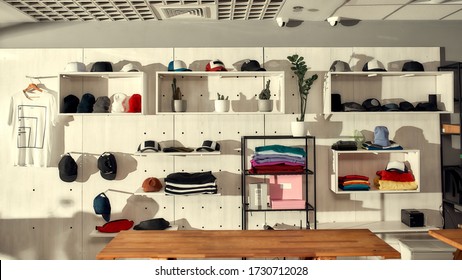 Custom Apparel, Clothes Neatly Arranged Or Folded On Shelves. Stack Of Colorful Clothing And Baseball Caps In The Store. Horizontal Shot