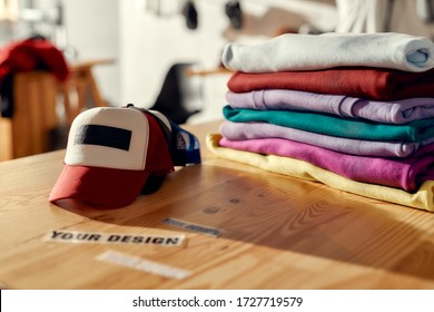 Custom apparel, clothes neatly folded on shelves. Stack of colorful clothing and baseball cap in the store. Horizontal shot. Selective focus
