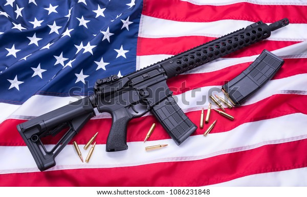 Custom built AR-15\
carbine, bullets and a magazine on American flag surface,\
background. Studio shot.