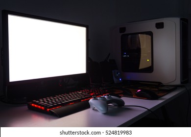 Custom Built Gaming Computer With White Screen, Keyboard, Mouse, Joypad, Gaming Chair Under Low Light. Selective Focus.