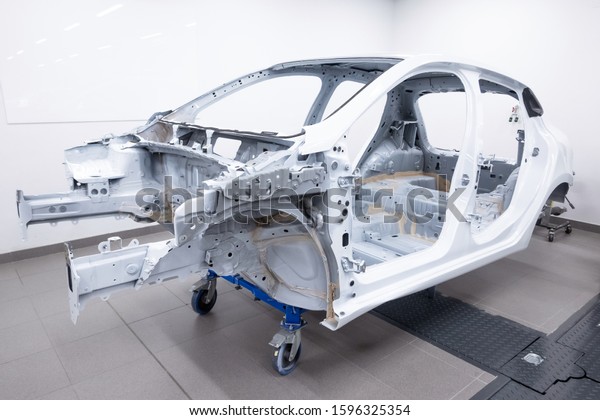 Custom car being build in workshop.\
Sports car body, car frame is assembled by mechanics. Metallic auto\
chassis in the air, car skeleton in\
service