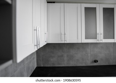 Custom kitchen cabinets installation with a white furniture facades mdf. Gray modular kitchen from chipboard material on a various stages of installation. A frame furniture fronts mdf profile.