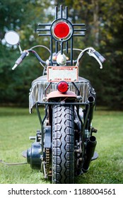 Custom Old School Motorcycle. Sitting On Grass With Trees Background. Vertical Image With Hand Made Sissy Bar In Cross Style. 