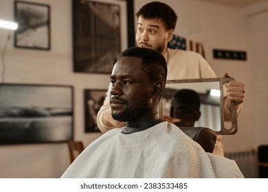 Customer admiring his haircut in barber shop - Powered by Shutterstock