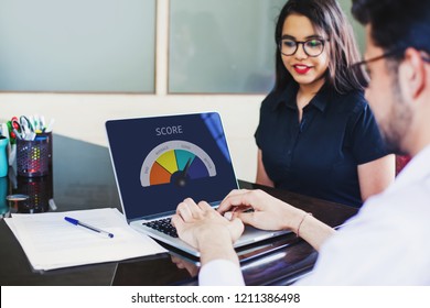 Customer Assessment In Bank. Credit Score On A Screen Of Laptop Appears As Indian Credit Scoring Officer Evaluates The Female Client.