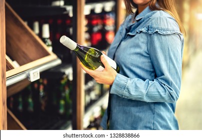 Customer Buying White Wine Or Sparkling Drink. Alcohol Aisle In Store Or Supermarket. Woman Holding Bottle. Buying Riesling Or Chardonnay. Shelf Full Of Drink Choices. Shopping Spirits.