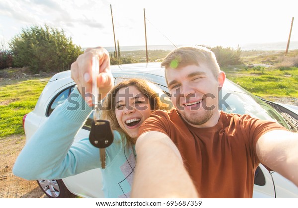 Customer, car sale, deal and people\
concept - laughing cheerful couple with a car holding\
keys.