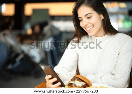 Customer checking smart phone sitting in a restaurant