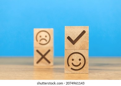 Customer choose positive smiley face and blurred sad face icon on a wooden cubes. Concept of service rating, satisfaction, business marketing background 