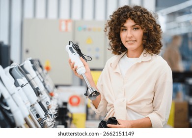 Customer comparing different models of immersion blenders in an appliance store, making purchasing decisions for kitchenware