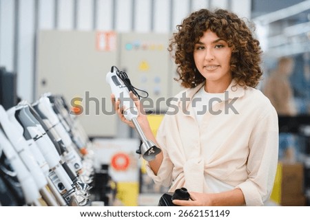 Customer comparing different models of immersion blenders in an appliance store, making purchasing decisions for kitchenware