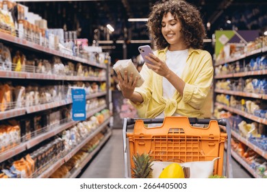 Customer comparing products information using a smartphone app while grocery shopping in a supermarket
